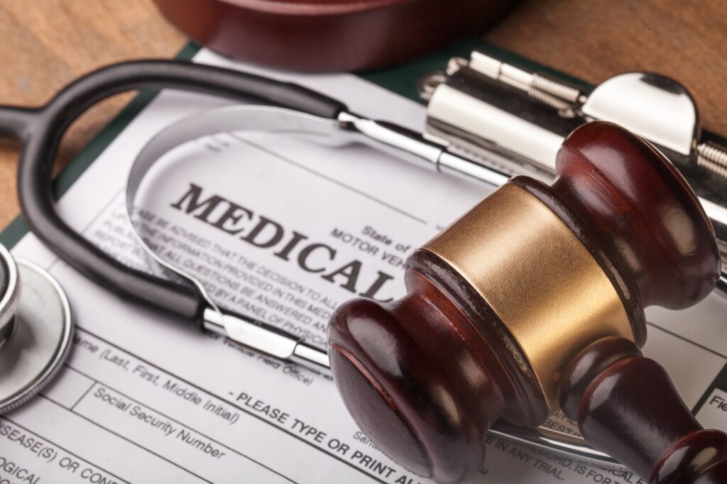 Documento médico con un martillo de juez y un estetoscopio, representando la regulación del Decreto 4725 de 2005 en el mantenimiento de equipos biomédicos.