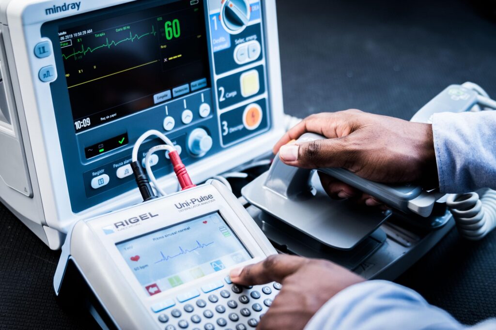 Técnico biomédico realizando pruebas de mantenimiento en un desfibrilador como parte de las estrategias de mantenimiento de equipos médicos.