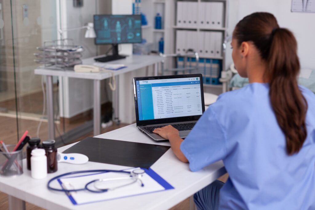 Profesional de la salud gestionando el inventario de equipos médicos en su ordenador, esencial para el mantenimiento efectivo de la tecnología médica